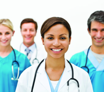 Portrait of four young smiling doctors in uniform over white background